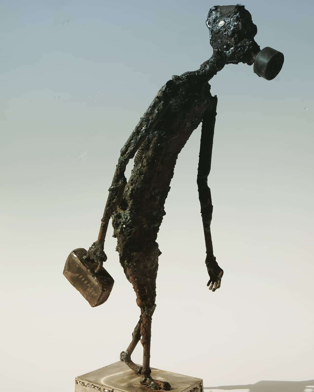 Escultura de Pedro Cuellar: figura delgada de metal caminando con una maleta