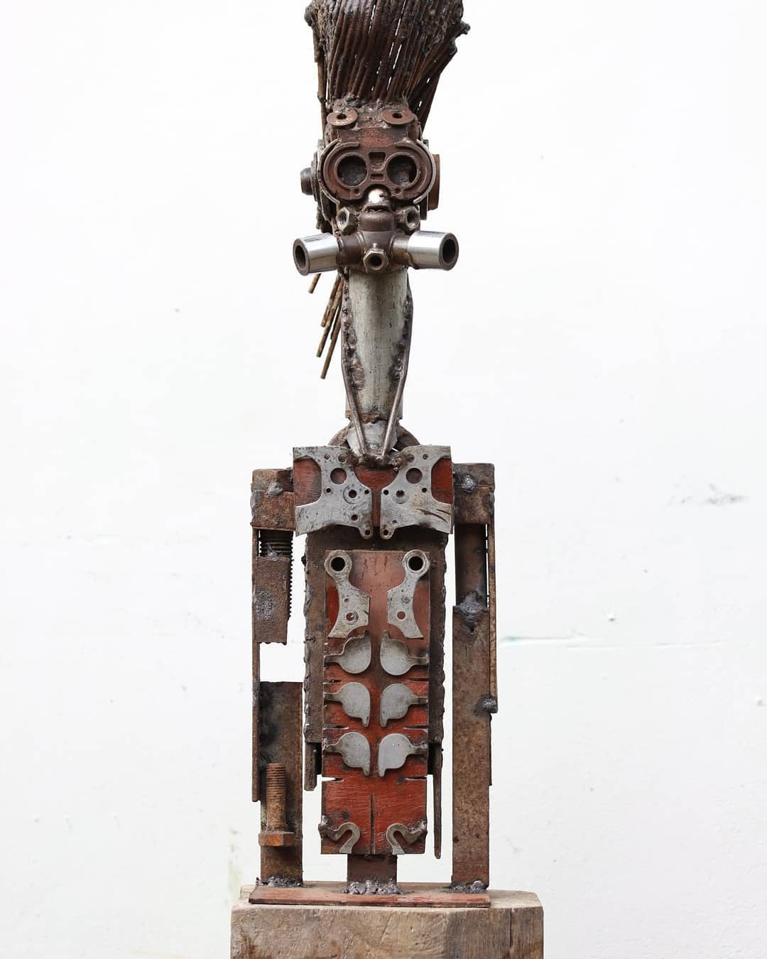 Escultura de Pedro Cuellar: figura alta de metal con un penacho de láminas en la cabeza