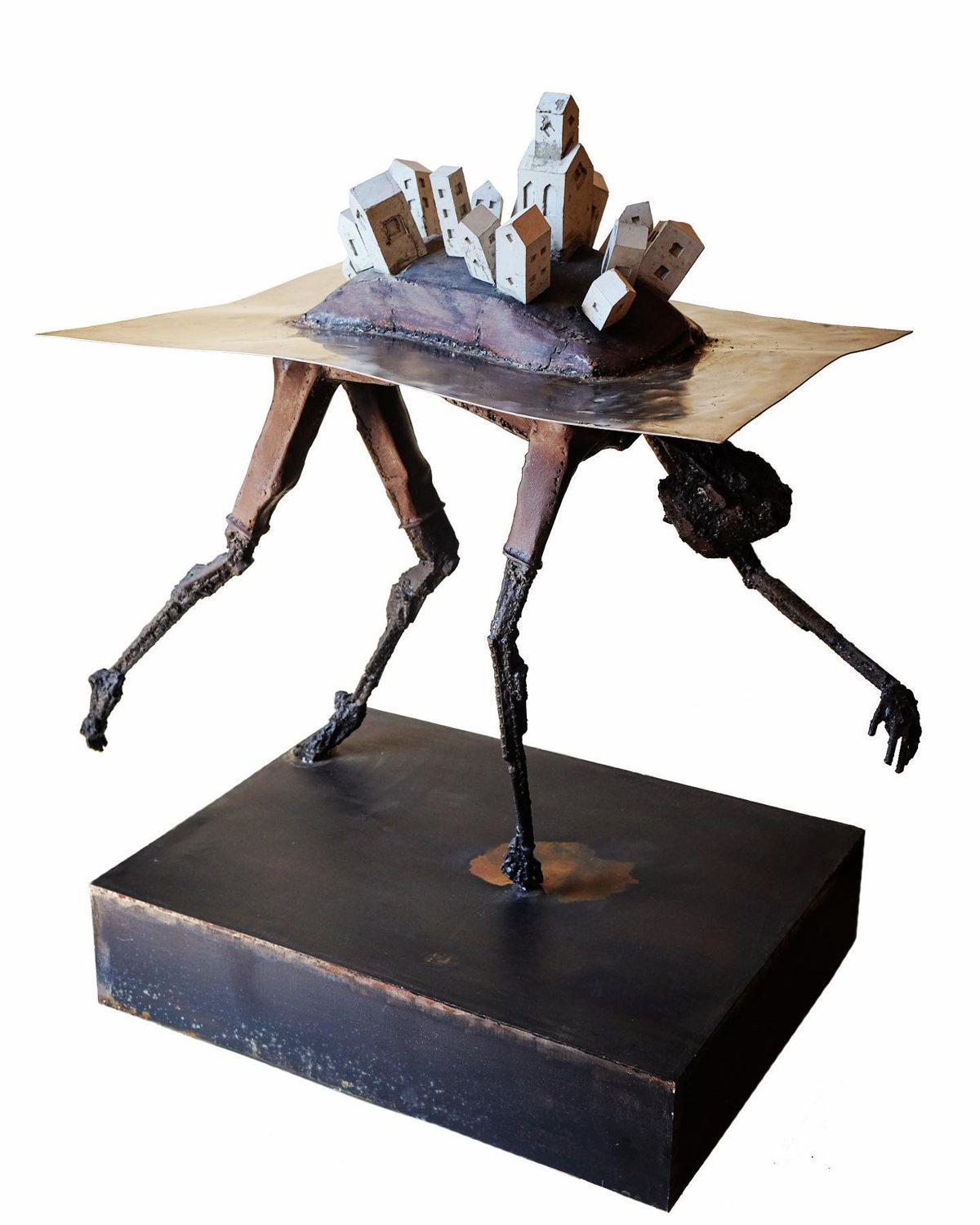 Escultura de Pedro Cuellar: mesa de metal con patas de figuras que carga un pueblo de casitas